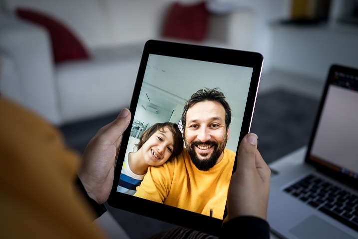 Foto einer Person, die ein Tablet-Gerät mit einem Videoanruf hält