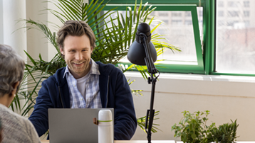 Young man, depicted in small business setting with laptop in modern workplace.
