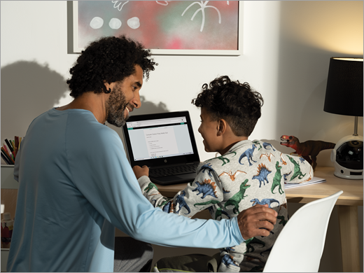 Een vader en zoon zitten samen achter een computer te smillen