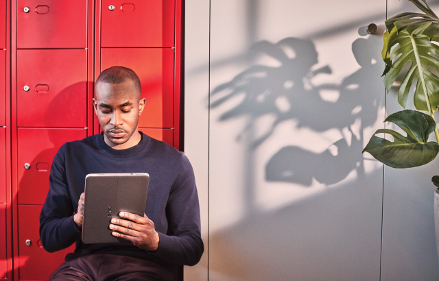 Een afbeelding van een man die in een gang zit en digitale notities maakt op een Windows-tablet